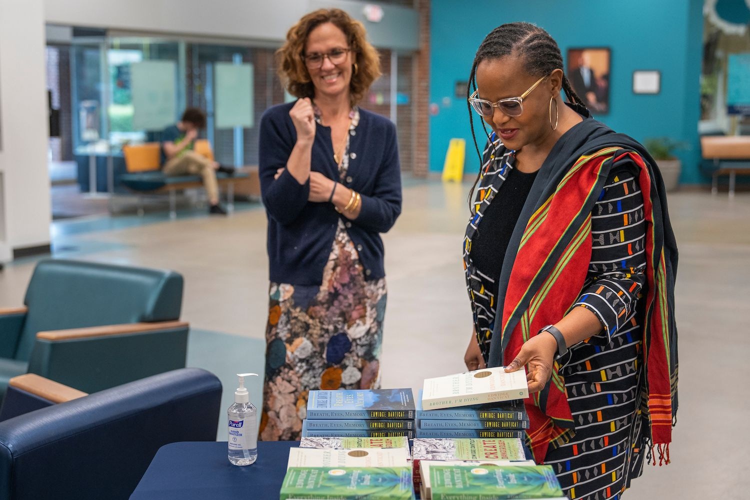 Two women looking at books on a table written by Edwidge Danticat