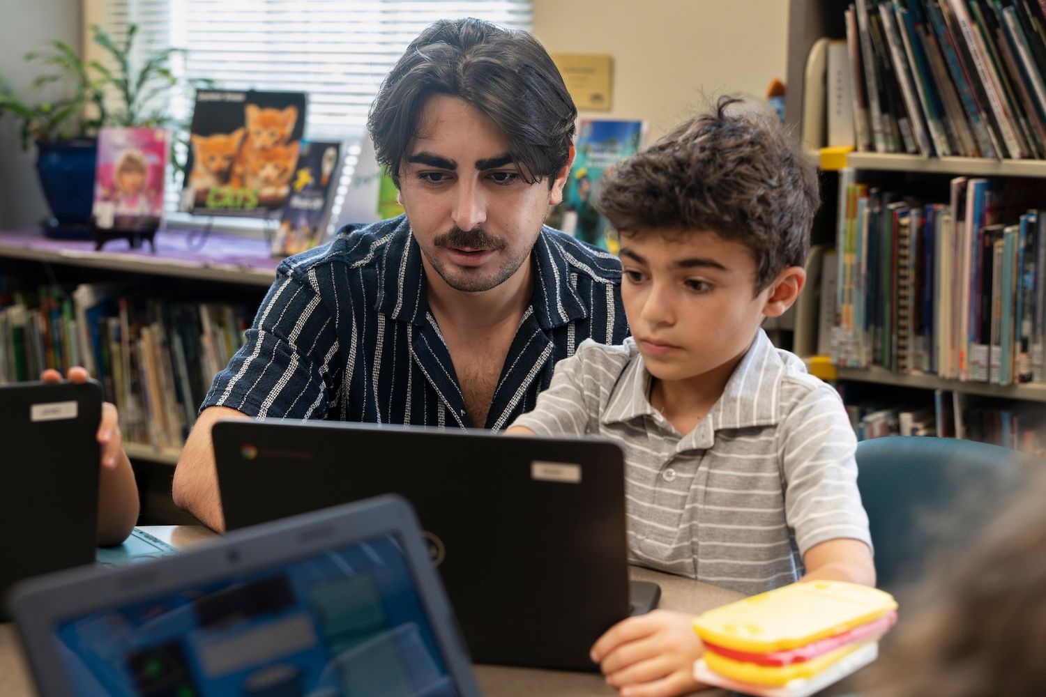 Person helping student navigate on a computer
