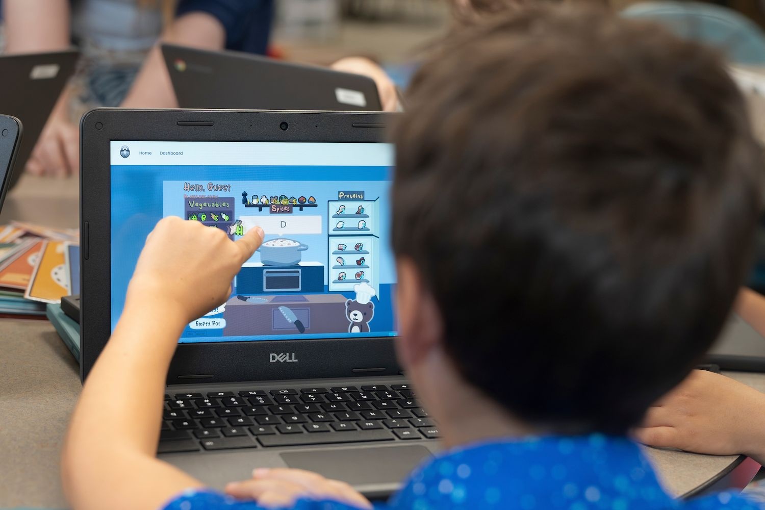 Kid pointing at his laptop screen while working on schoolwork