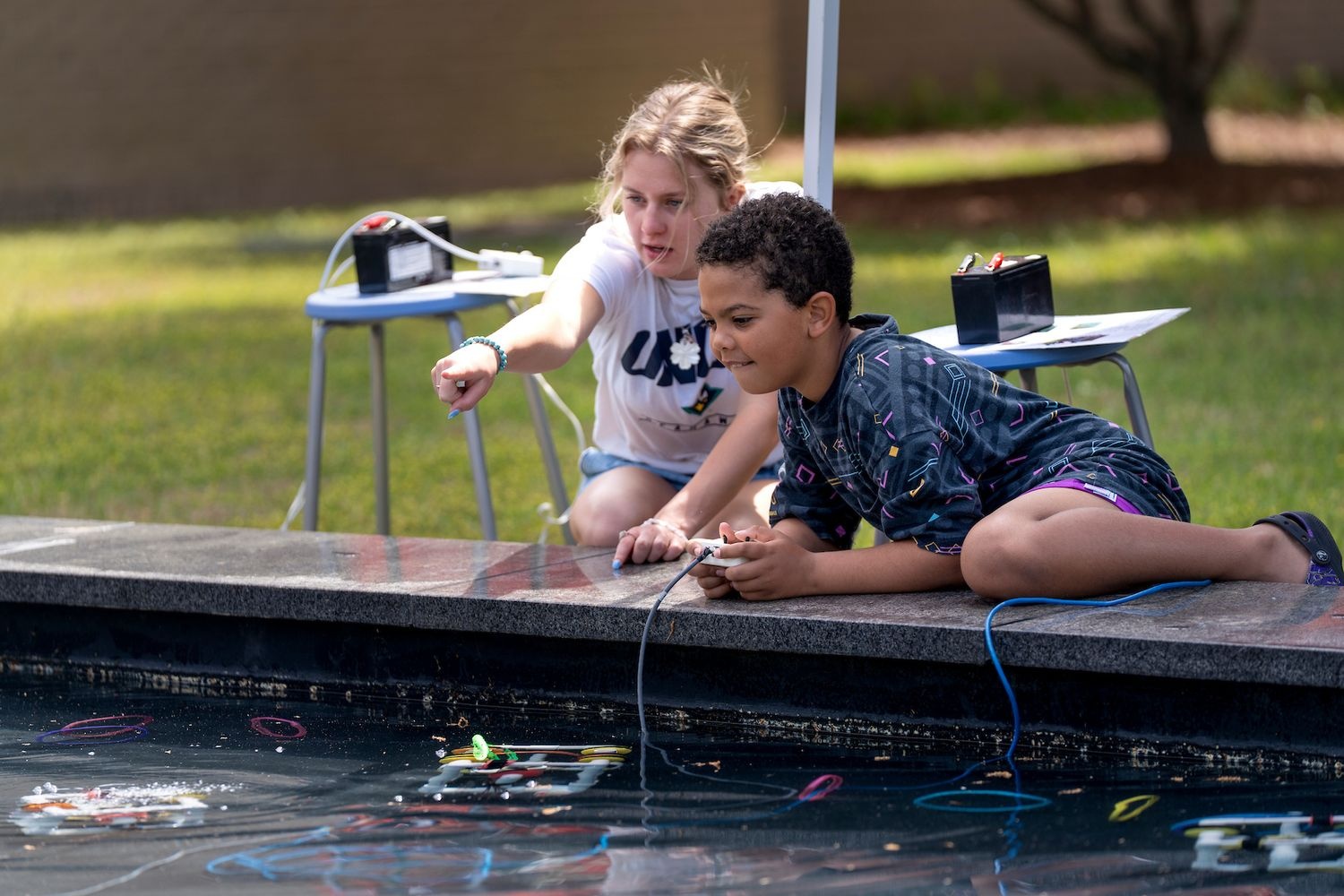 Two children driving a remote controlled device in the water