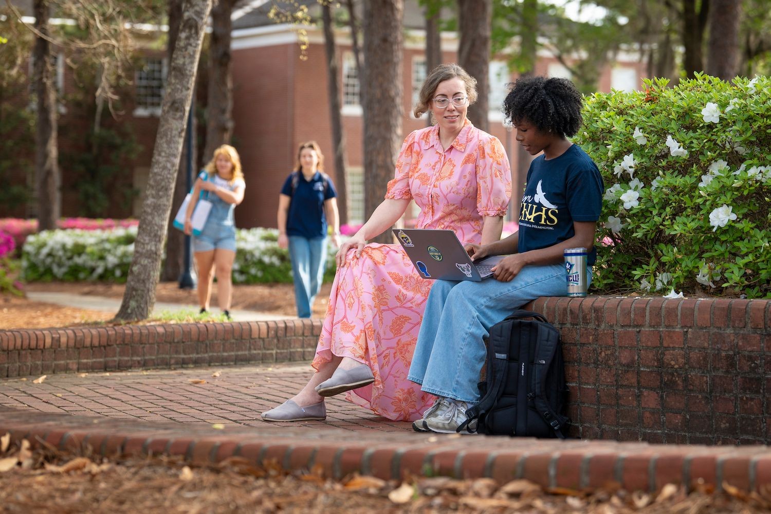 Students studying outside with a laptop on a bench