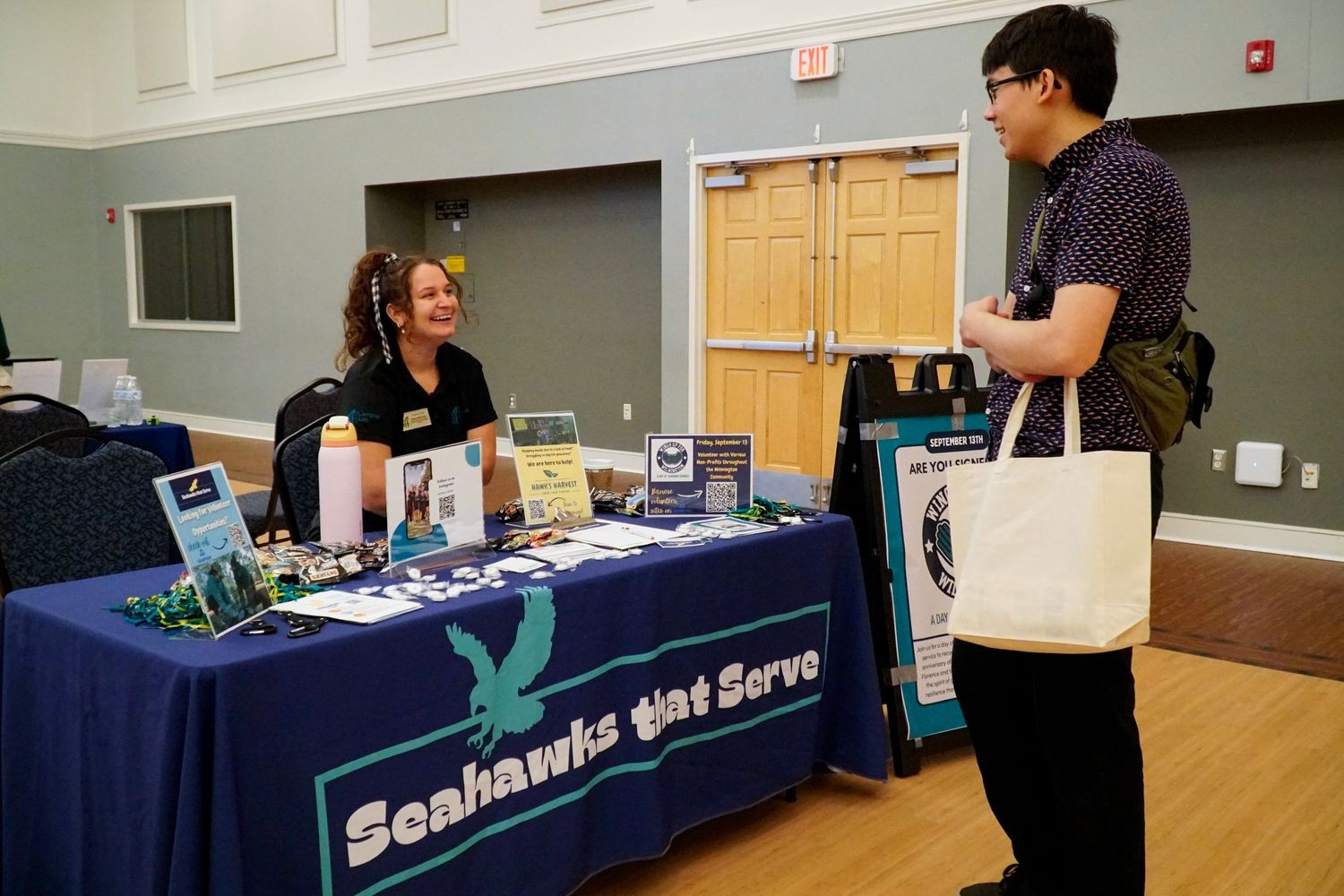 Student speaking with a volunteer at a Seahawks that Serve booth