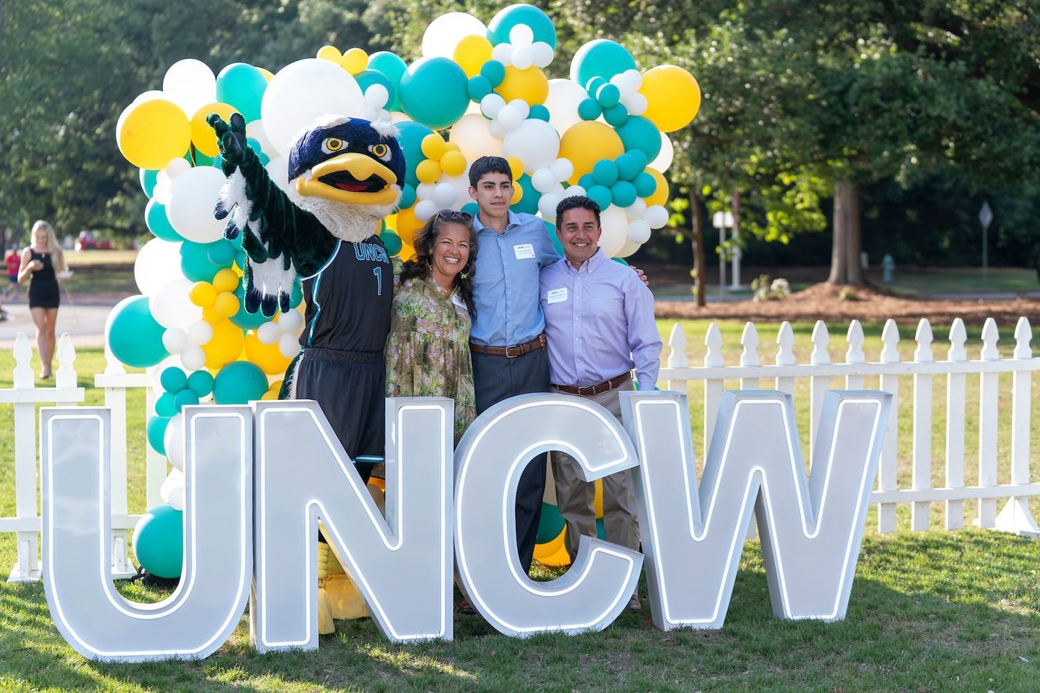 Sammy C. Hawk poses with people and the letters UNCW 