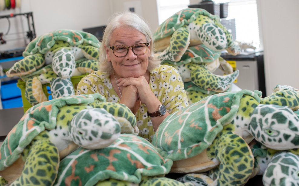 Smiling with many plush sea turtles laying around