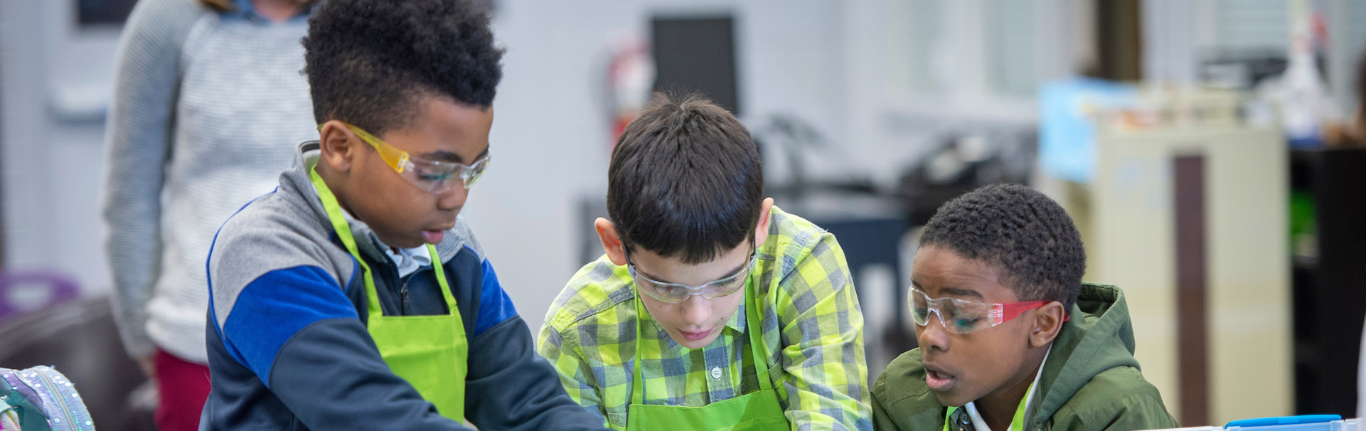 Young students with aprons and gloves on operating in a science lab