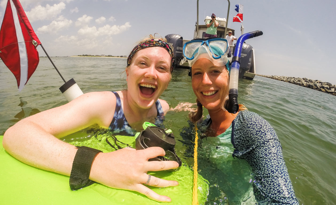 2 students diving behind a boat