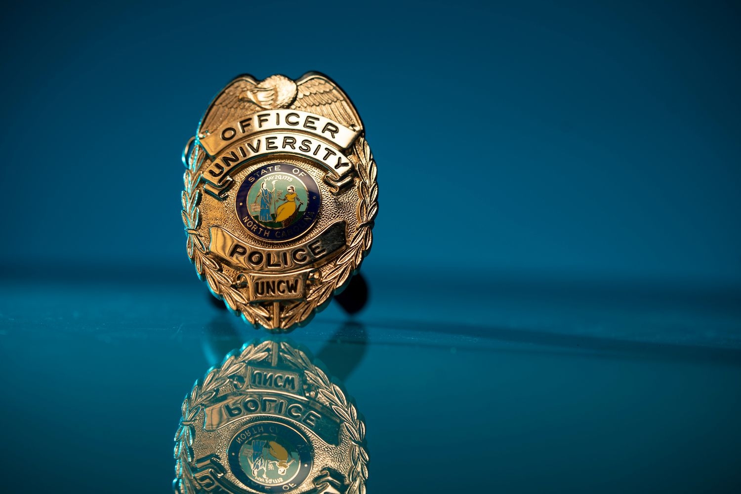 UNCW police badge on a teal background